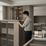 Vela Home Global - Dedicated China sourcing agent team member performing rigorous quality control inspection on bespoke joinery using a laser measurement tool and digital caliper in a Foshan workshop.